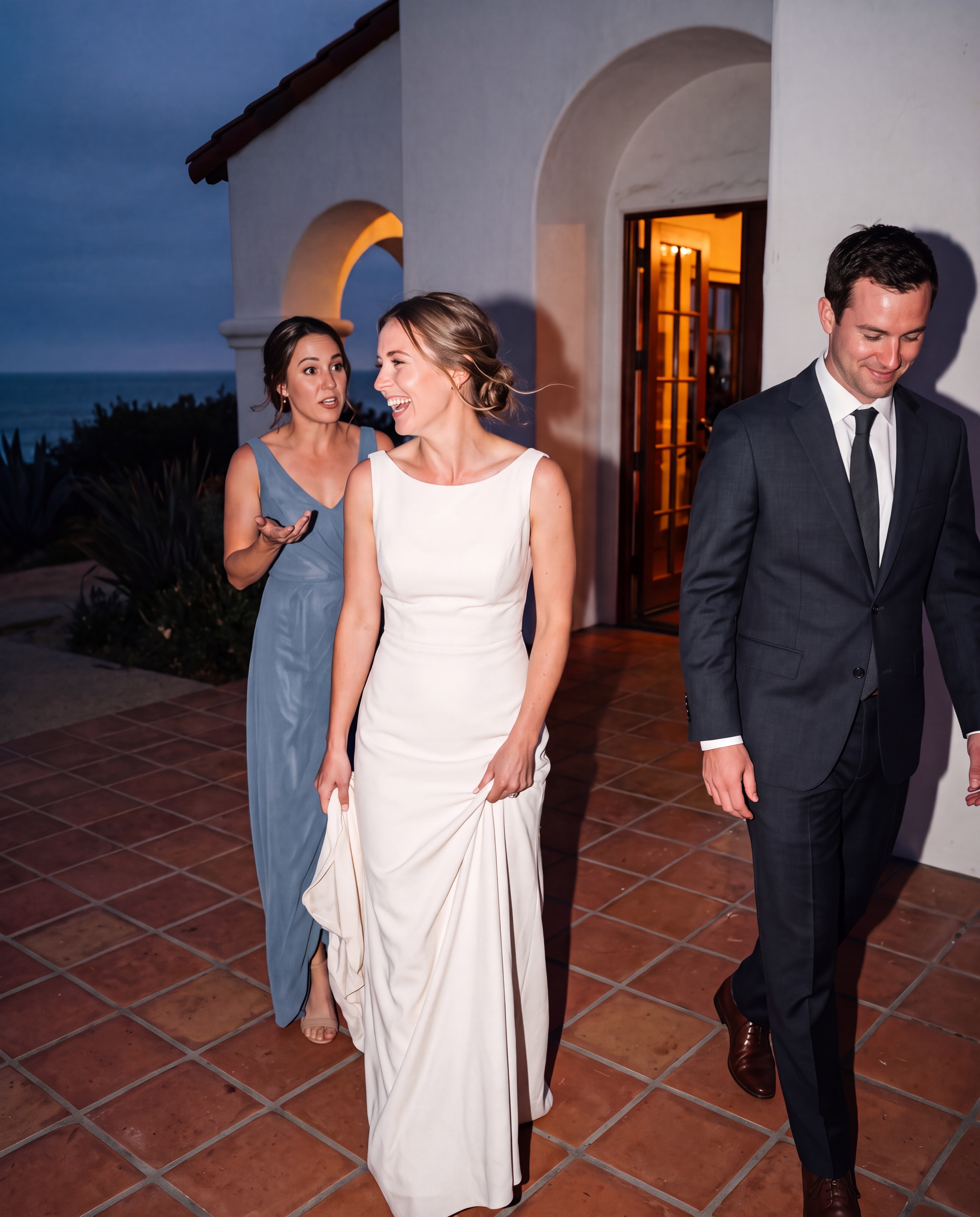Three adults laughing during a direct-flash coastal wedding exit with natural expressions.